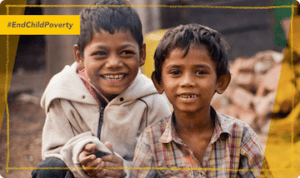 An image of two young boys in rubble who are still smiling at the camera with the tag, 'End Child Poverty' added in the corner.