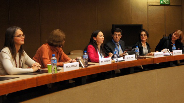 An image of multiple speakers for Arigatou International's side event sitting at a long table together, discussing amongst one another.