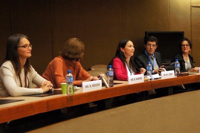 An image of multiple speakers for Arigatou International's side event sitting at a long table together, discussing amongst one another.