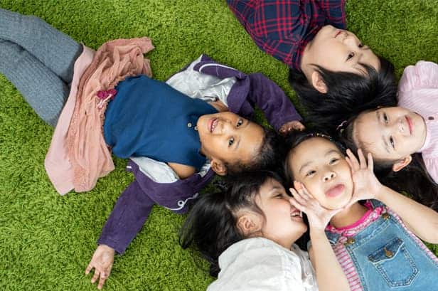 Children laying on the floor, huddled up making silly faces.