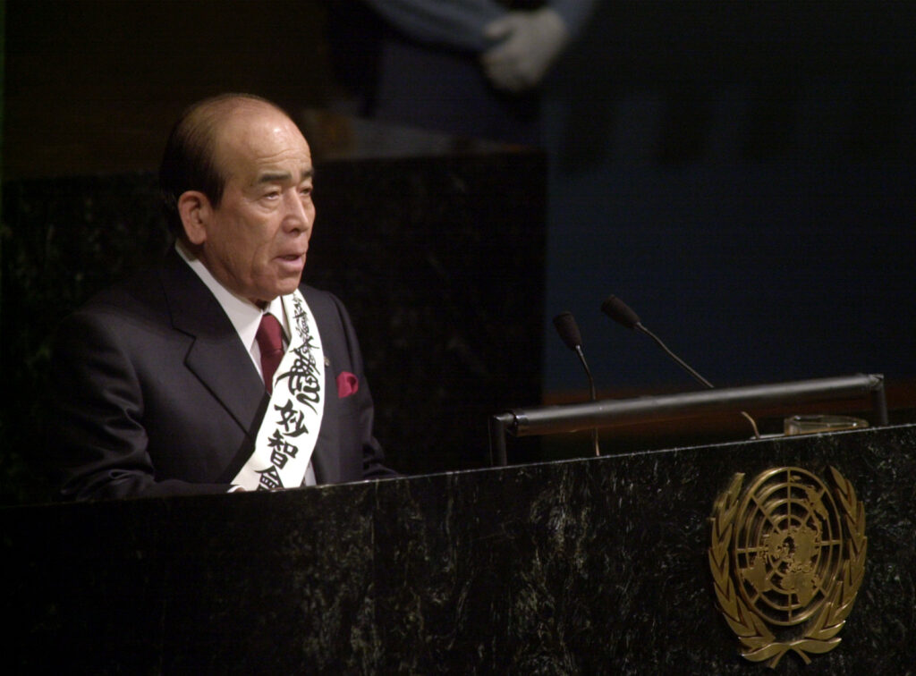 Rev. Takeyasu Miyamoto speaking at the UN GA hall rostrum; 
